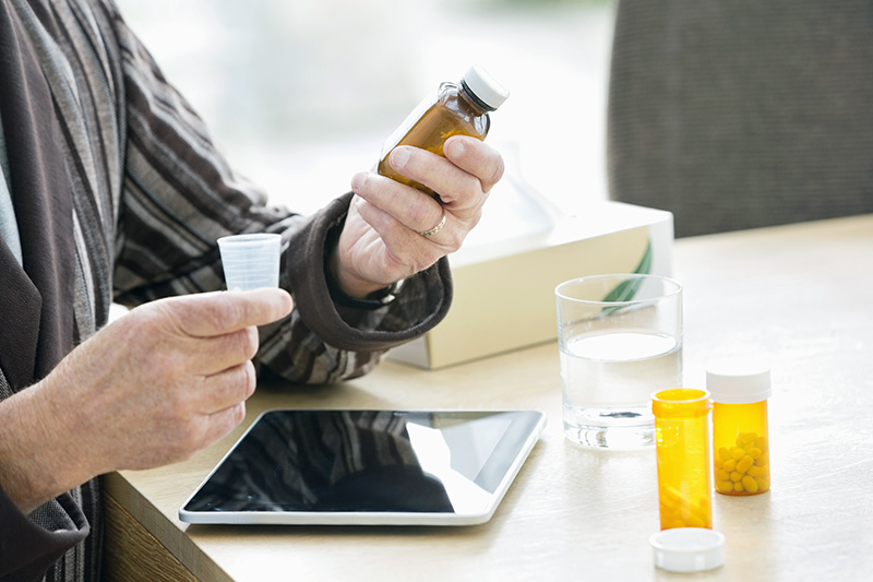 Older man taking medications at table