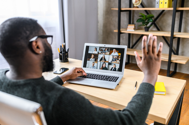 A man talking online with employees via video call