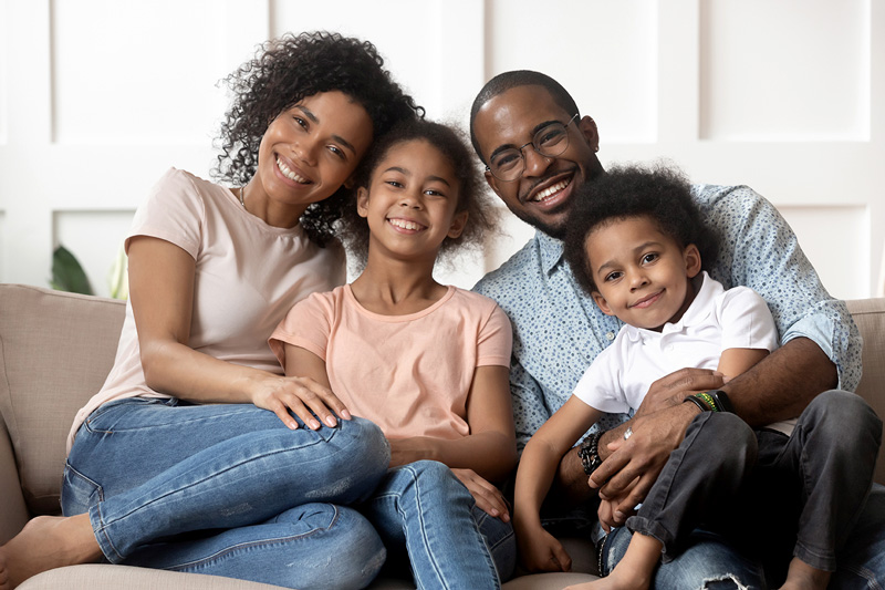 Portrait of happy young black family with little kids sitting on the couch smiling