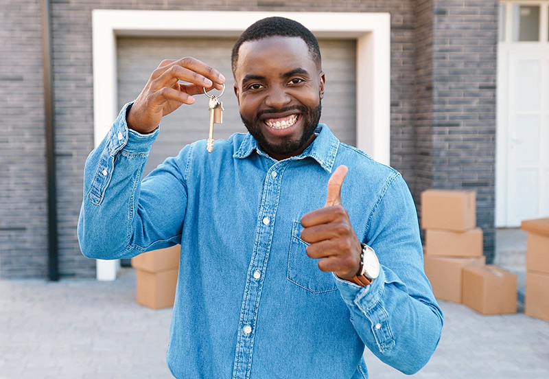 A happy black young man showing a key to his new housing