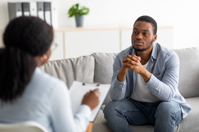 Depressed male patient having psychotherapy session with counselor at mental health clinic