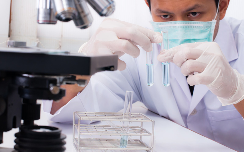 A doctor working with a microscope in laboratory room performing scientific research.