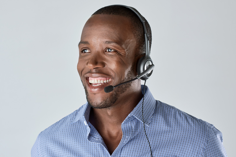 Black man helping a caller over the phone wearing a headset
