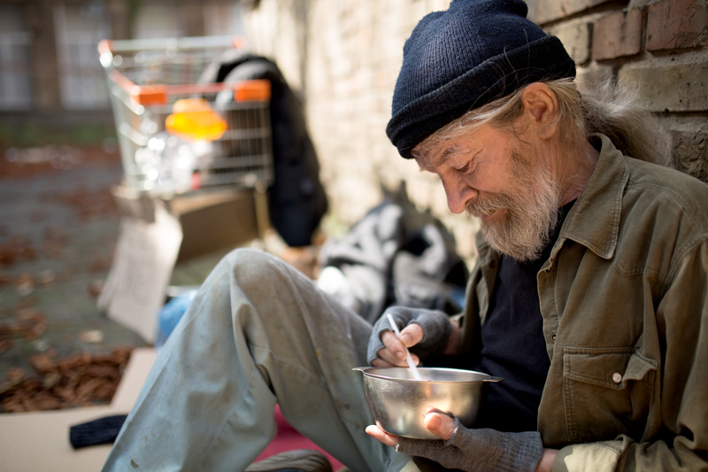 Homeless man holding a bowl of food
