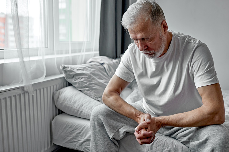 an older man sitting alone at home, feeling lonely and isolated