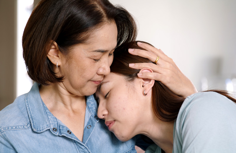 An Asian mother comforting her teen daughter