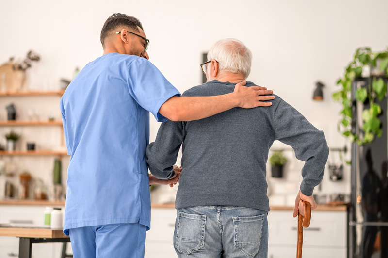nurse helping elderly man walk on a cane