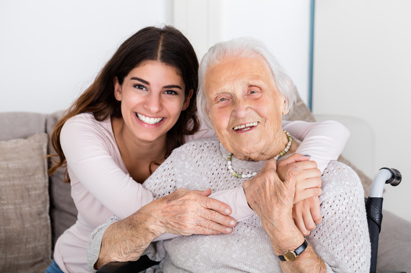 A young woman hugs an elderly woman as they smile for the camera