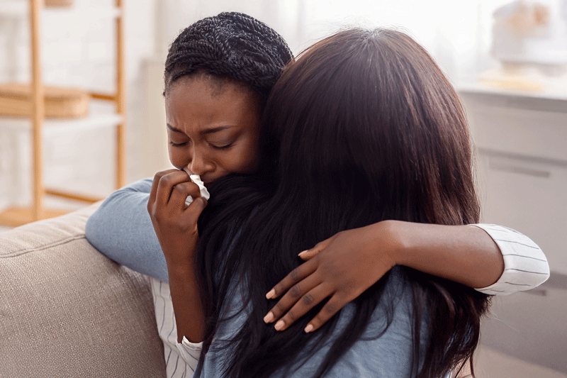 Woman hugging her crying girlfriend, supporting her after receiving bad news