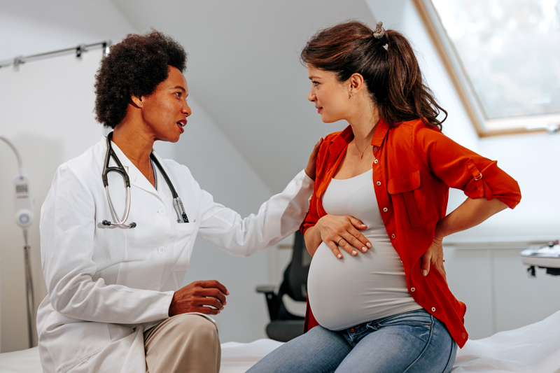Doctor advising pregnant woman at hospital.