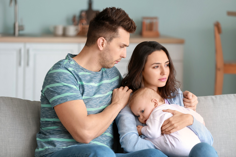 Young father with baby and wife suffering from postnatal depression at home