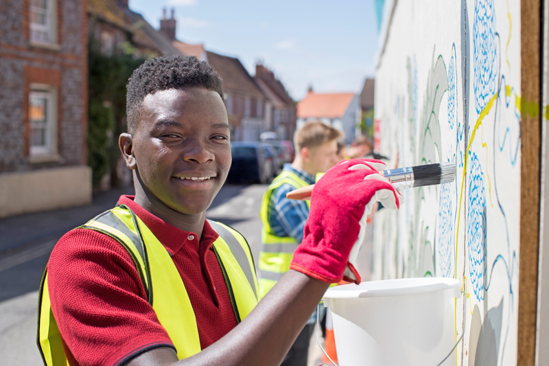 Group Of Helpful Teenagers Creating And Maintaining Community Art Project